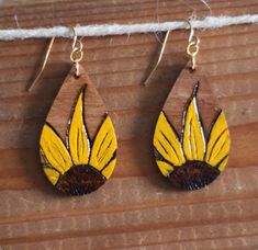 two yellow and brown earrings hanging from a string on a wooden surface with white thread