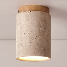 a concrete light fixture hanging from a ceiling with a wooden holder on the wall behind it