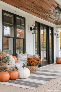 pumpkins and gourds are sitting on the front porch