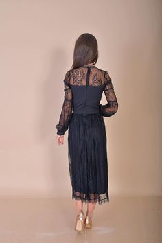 a woman wearing a black dress with sheer sleeves