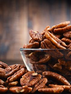 a bowl full of pecans sitting on top of a table next to a plant