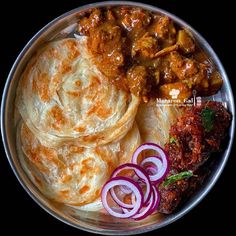 a plate full of food with onions and meats on it, including roti bread