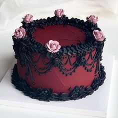 a red and black cake with pink flowers on top