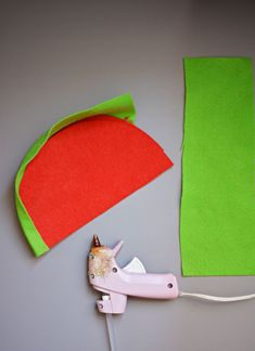 a pair of pink scissors next to a piece of green felt and a sewing needle