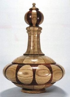 a wooden vase sitting on top of a white table next to a light bulb with circles painted on it