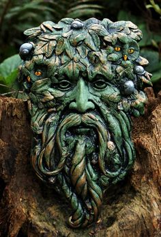 a green man's face is shown on a tree stump