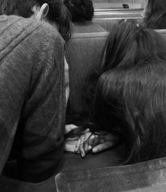 several people sitting on a bus with their hands in the back of one person's head