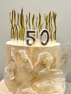 a 50th birthday cake with white frosting and gold sprinkles on top