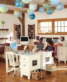 two children are sitting at a desk with globes hanging from the ceiling