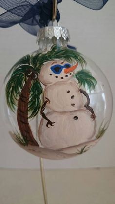 a glass ornament with a snowman on it's head and palm tree