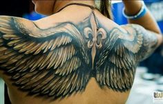 the back of a woman's shoulder with an eagle tattoo on it and scissors