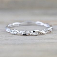 a white gold wedding band with two diamonds on it, sitting on a wooden surface