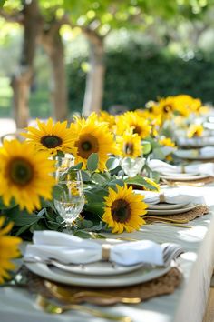 a long table with sunflowers on it and place settings in front of them