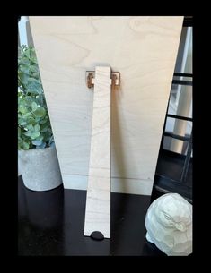 a piece of wood sitting on top of a table next to a potted plant