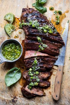 sliced steak with green sauce and garnish on cutting board