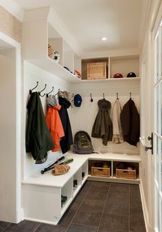 a white bench sitting under a window next to a coat rack with coats on it