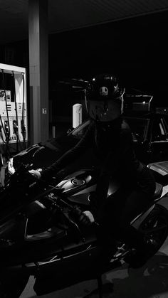 black and white photograph of a person on a motorcycle in a parking lot at night