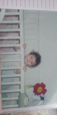 a young child standing in front of a ladder with a stuffed flower on the bottom