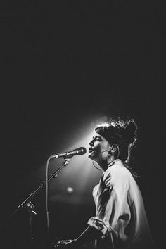 a woman singing into a microphone while standing in front of a microphone on a stage