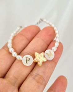 Add a touch of celestial elegance with this beautifully crafted bracelet, featuring a harmonious blend of freshwater rice pearls and a charming star-shaped pearl. Accented with two mother-of-pearl letter beads, this bracelet offers a personalized flair that makes it truly special. The centerpiece arrangement of letter, star, and letter beads can symbolize messages like "I ★ U" or "E ★ K," adding a unique and heartfelt touch. The bracelet is completed with a 925 sterling silver adjustable clasp, White Charm Bracelet With Star Charm As Gift, Star-shaped Jewelry With Pearl Charm As A Gift, Star-shaped Jewelry With Pearl Charm Gift, Star-shaped Pearl Jewelry For Gift, Personalized White Pearl Bracelet, Personalized Pearl Bracelet For Mother's Day, White Dainty Pearl Bracelet For Birthday, Dainty White Pearl Bracelet For Birthday, Pearl White Hypoallergenic Bracelet As A Gift