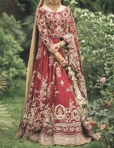 a woman in a red and gold bridal gown posing for the camera with her hands on her hips