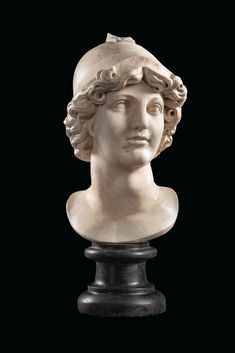 a white marble bust of a man with curly hair and a hat on his head