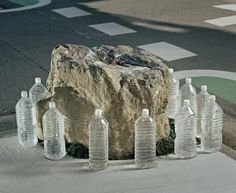 several empty water bottles sitting on the ground next to a large rock and crosswalk