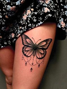 a woman's thigh with a butterfly tattoo on the side of her leg,