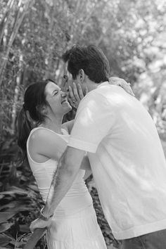 a man and woman are kissing in the woods