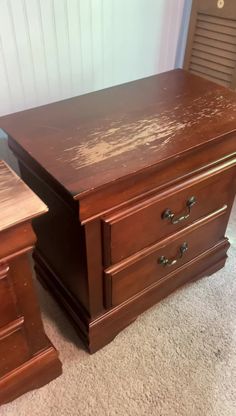 a brown desk with two drawers on top of it and a chair in the background