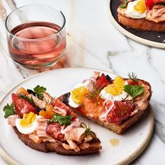 two plates with food on them next to a glass of water and a plate with an open face sandwich