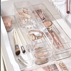 the drawers are filled with makeup and other items in clear plastic containers on top of a white countertop