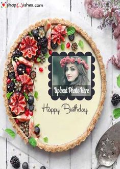 a birthday cake decorated with fruit and flowers on top of a white wooden table next to a spoon