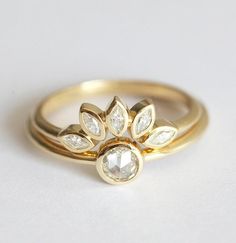 two gold wedding rings with diamonds on each one, set against a plain white background