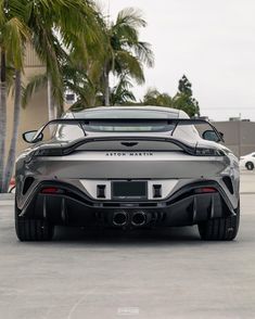 a silver sports car parked in front of palm trees