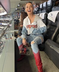 a woman sitting in the bleachers with her mouth open and wearing red cowboy boots