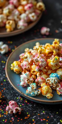 two plates filled with popcorn and sprinkles on top of a black table