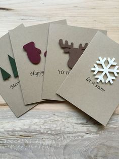 four christmas cards with reindeer and snowflakes on them, sitting on a wooden surface