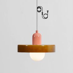 a pink and brown lamp hanging from a light fixture with an electrical cord attached to it