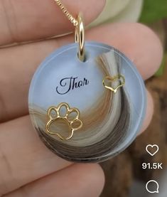 a person holding a dog's paw charm in their hand with the name thor on it