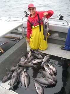 a man in yellow overalls holding a fish on a boat with other people nearby