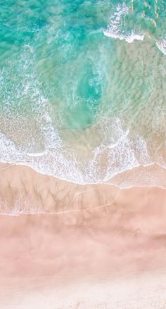 an aerial view of the ocean and beach with waves crashing on it's shore