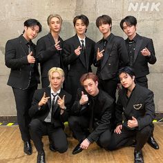 a group of young men in suits posing for the camera with their thumbs up signs