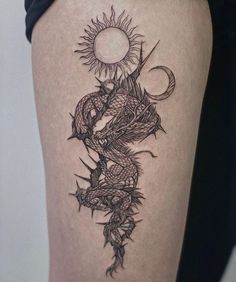 a woman's thigh with a dragon and sun tattoo on it