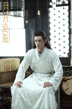 a man sitting on top of a couch wearing a white robe