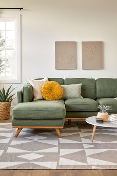 a living room with a green couch and two paintings on the wall above it that says timber sectional