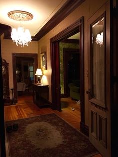 a hallway with a chandelier and two lamps on either side of the door