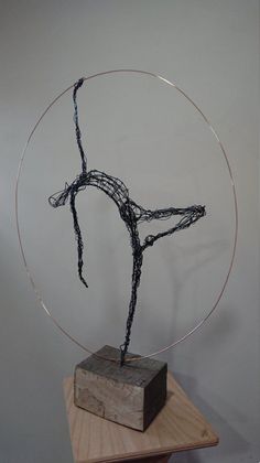 a wire sculpture sitting on top of a wooden block