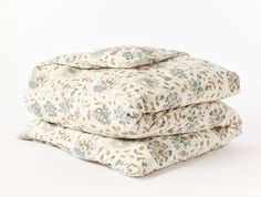 three pillows stacked on top of each other in front of a white background with blue and green flowers