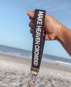 a person holding up a keychain that says make heaven sound on the beach